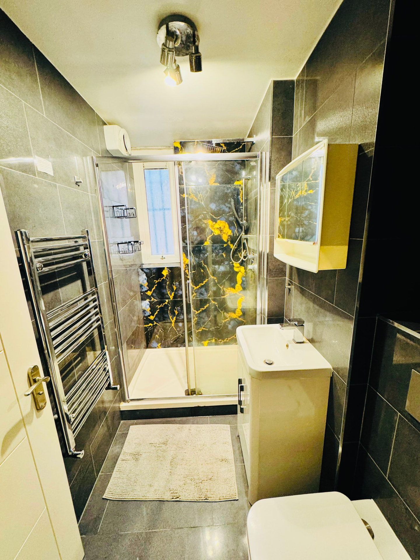 Modern shared bathroom with walk-in shower, heated towel rail and marble tiles